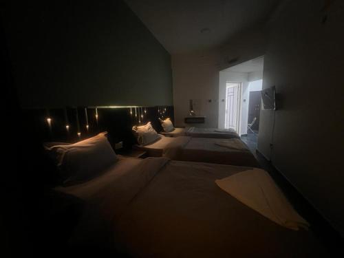 a room with three beds in a dark room at GUEST INN HOTEL in Dubai