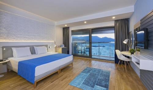 a bedroom with a bed and a desk and a window at Hotel Kaptan in Alanya