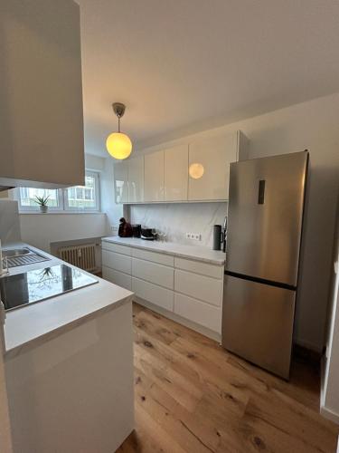 a kitchen with white cabinets and a stainless steel refrigerator at Sweet Home in Meerbusch in Meerbusch