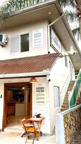 a restaurant with a table in front of a building at MORADA GARAPEIRA in Guarda do Embaú