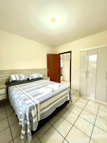 a bedroom with a bed with a blue and white blanket at MORADA GARAPEIRA in Guarda do Embaú