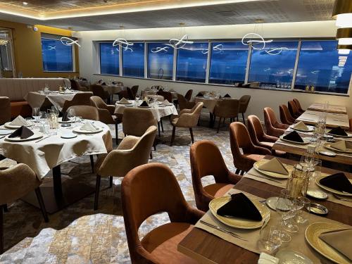 una sala da pranzo con tavoli, sedie e finestre di LE MANOIR DU ROSELIER HOTEL 3 étoiles a Plérin