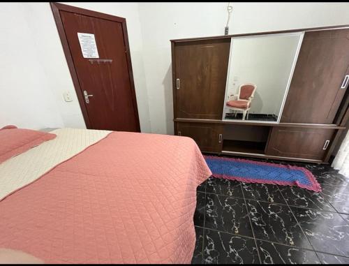 een slaapkamer met een bed en een stoel in een spiegel bij Pensão da Rose in Sorriso