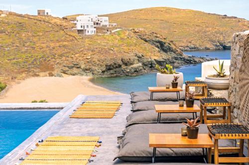patio z krzesłami i stołami przy basenie w obiekcie Sea Rock & Sky Private Mykonos Residence w mieście Merchia Beach