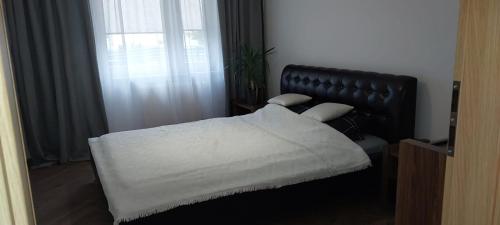 a bedroom with a bed with white sheets and a window at Apartament przy Stawie in Wrocław