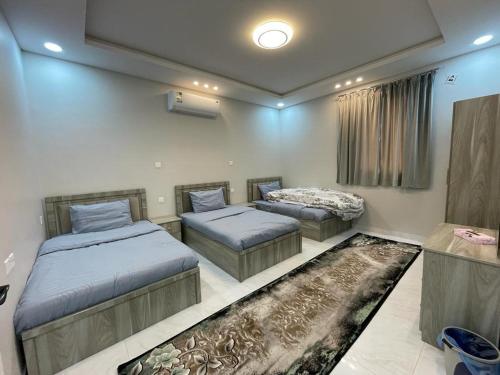a bedroom with two beds and a rug at شاليهات وجدان الهدا in Al Hada