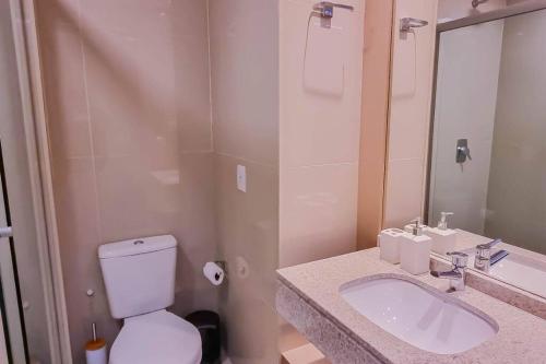 a bathroom with a toilet and a sink and a mirror at Blend Smart Marista 2 Quartos in Goiânia