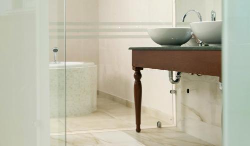 a bathroom with a sink and a mirror and a tub at Electra Hotel in Stavros