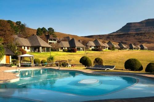 a large swimming pool in front of a group of huts at Fairways resort 6 sleeper unit in Drakensberg Garden