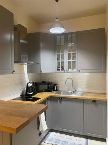 une cuisine avec des armoires blanches et un évier dans l'établissement Chemin Vert, à Paris