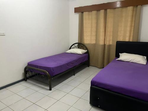 two beds in a room with purple sheets at Ziara Apartments in Nadi