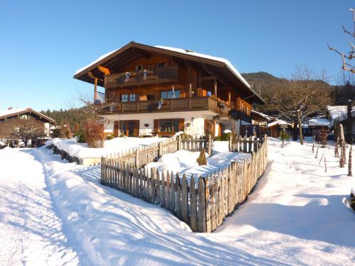 a wooden fence in the snow in front of a house at Gästehaus Schönfeld in Reit im Winkl