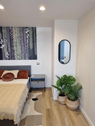 a bedroom with a bed and two potted plants at Apartament Spokojna przy SUNTAGO DEEPSPOT Mszczonów in Mszczonów