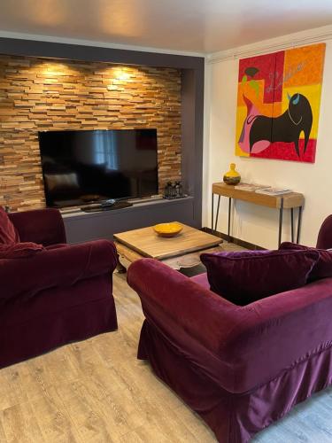 a living room with two couches and a flat screen tv at Gîte le 27 in Lorp Sentaraille