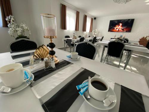 un comedor con mesas y sillas blancas en Rezydencja Myśliwska - Apartamenty, en Koszalin