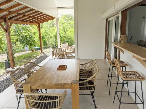 VILLA CAJOU DESIRADE في Baie Mahault: غرفة طعام مع طاولة وكراسي خشبية