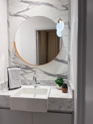 a bathroom with a white sink and a mirror at Fiusa Dream 153 in Ribeirão Preto