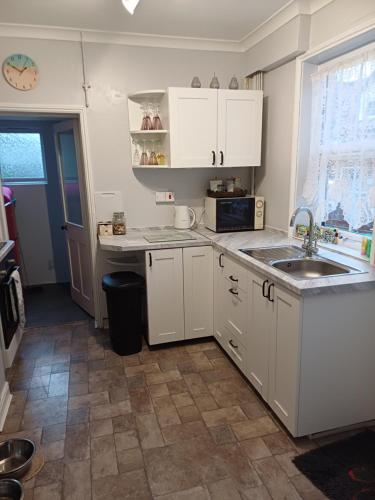 a small kitchen with white cabinets and a sink at Dune Cottage in Caister-on-Sea