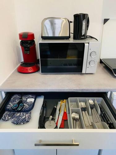 - une étagère de cuisine avec un four micro-ondes et des ustensiles dans l'établissement Le Havre 2 Paix, au Havre