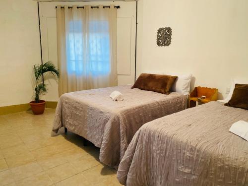 1 dormitorio con 2 camas y ventana en Villas Cairo, en Guatemala