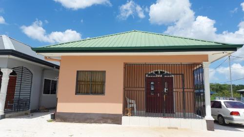 una pequeña casa con techo verde y puerta roja en Apartment Julia en Paramaribo