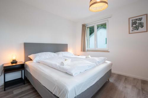 a bedroom with a bed with white sheets and a window at Moderne Wohnung mit Parkplatz - Top Floor in Ostermundigen