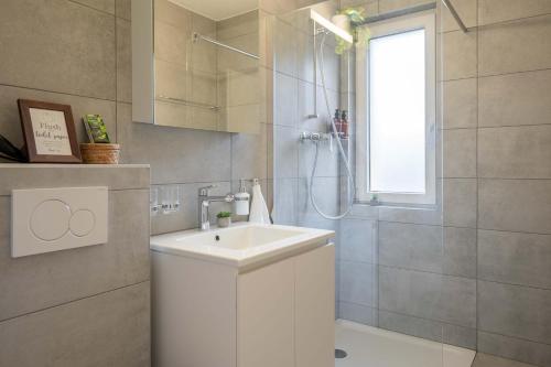 y baño con lavabo blanco y ducha. en Moderne Wohnung mit Parkplatz - Top Floor, en Ostermundigen