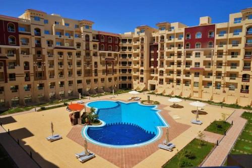 a large swimming pool with chairs and umbrellas in front of buildings at منتجع فلورانزا 50 in Hurghada