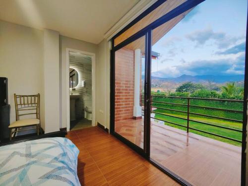 um quarto com uma porta de vidro deslizante para uma varanda em Hostería Quinta Esperanza - Alquiler del Alojamiento Entero em Loja