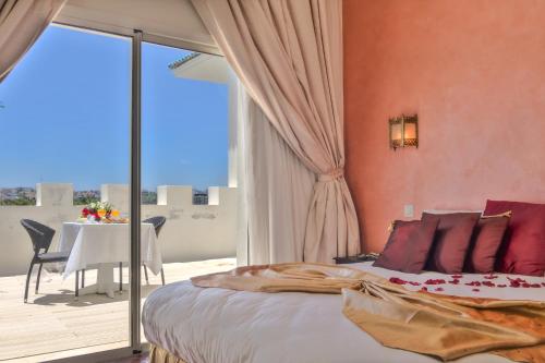 a bedroom with a bed and a balcony with a table at Palais du Calife Riad Spa & Clubbing in Tangier