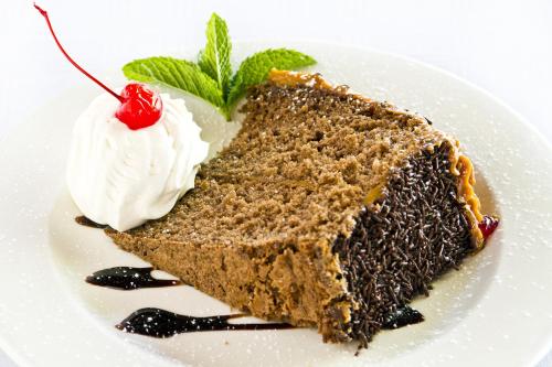 a piece of chocolate cake with whipped cream and a cherry at Arebbusch Travel Lodge in Windhoek