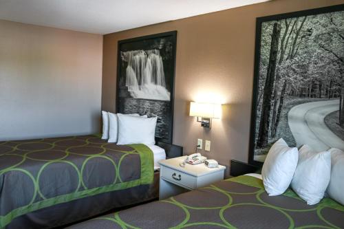 a hotel room with two beds and a painting on the wall at Super 8 by Wyndham Indianapolis Emerson in Indianapolis