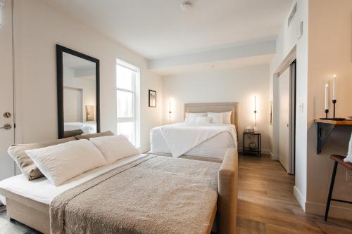 a white bedroom with a bed and a mirror at Elegant Apartment in the Heart of Hollywood in Los Angeles