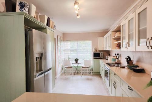 een keuken met witte kasten en een tafel met stoelen bij Easy living West Beach family home in Kaapstad
