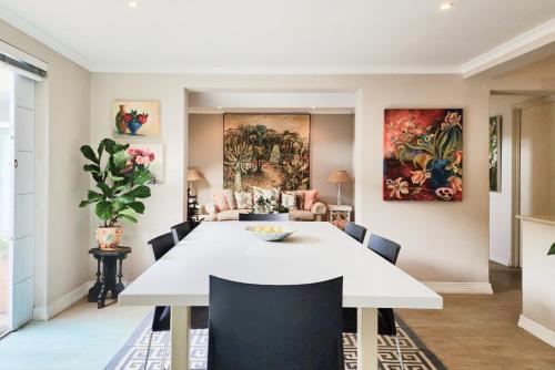 een eetkamer met een witte tafel en stoelen bij Easy living West Beach family home in Kaapstad