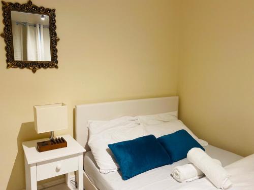 1 dormitorio con cama con almohadas azules y espejo en Stylish 1 bedroom Haven en Coventry