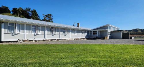 eine Reihe weißer Gebäude mit einem Grasfeld in der Unterkunft The Headland Lodge in Gisborne