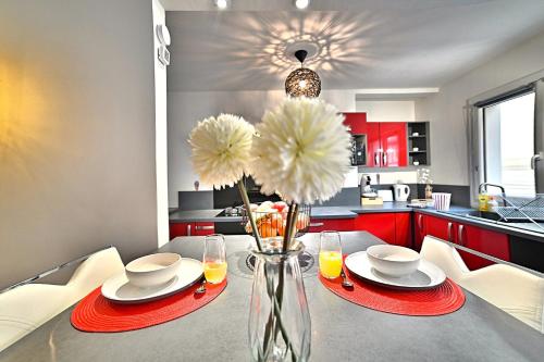 une cuisine avec une table avec des armoires rouges et un vase avec des fleurs dans l'établissement Dolce Vita - Hypercentre - TV 4K - Fibre - Netflix, à Saintes