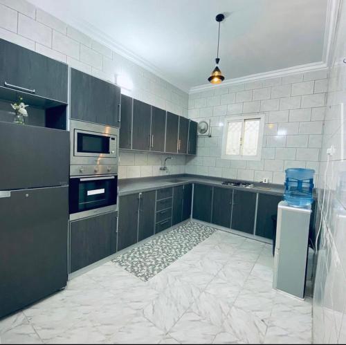 uma cozinha com armários cinzentos e piso em azulejo branco em فيلا 109 الطائف الشفا em Al Shafa