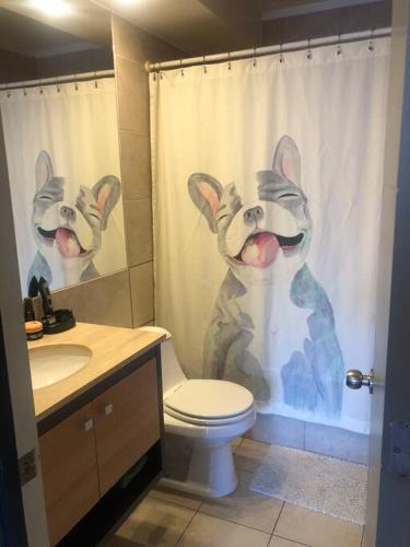 a bathroom with a toilet with a dog shower curtain at Espectacular departamento in Viña del Mar