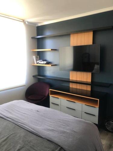a bedroom with a bed and a flat screen tv at Espectacular departamento in Viña del Mar