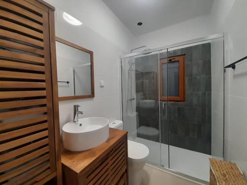 a white bathroom with a sink and a shower at Adcasinha em Arganil in Adcasal