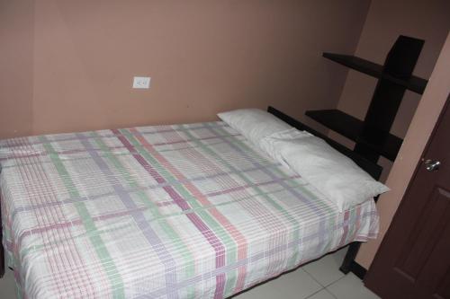 uma cama com um cobertor xadrez e duas almofadas em Hotel Pecos Bill em San José