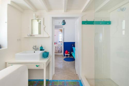 a white bathroom with a sink and a shower at seasalthouse - famous tv location in Koskinou