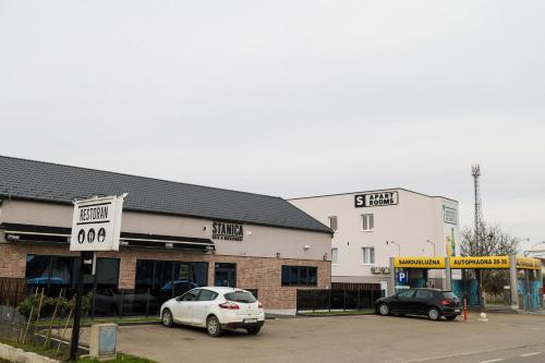 two cars parked in a parking lot next to buildings at S Apart Rooms in Bosanska Gradiška
