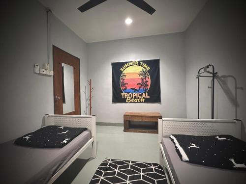 a room with two beds and a poster on the wall at Junest Hut in Pantai Cenang