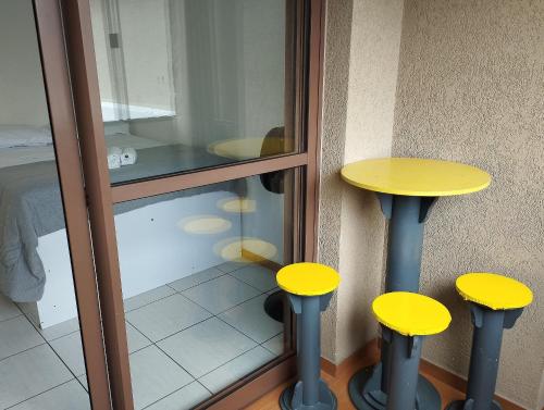 a couple of yellow stools sitting next to a window at Apto 1Q 300MB Fibra Ótica Próx Shop Estação in Curitiba