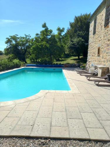 - une piscine à côté d'un bâtiment en pierre dans l'établissement Domaine de La Bertrandie, à La Fouillade