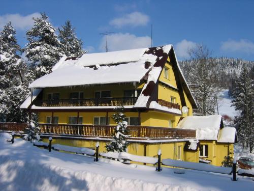 ティリチにあるOśrodek Wypoczynkowy BARTAの屋根に雪が積もった黄色い家