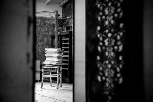 a room with a chair and a stack of books at Inter Artes Prestige House and Luxury Suite in Viterbo